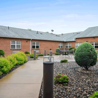 A landscaped courtyard with a pathway surrounded by shrubs and a brick building.