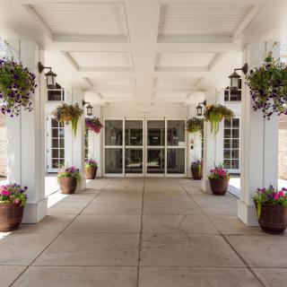 A building entrance with decorative columns and hanging plants.