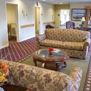 A cozy lounge area with patterned sofas and a wooden coffee table on a red carpet.