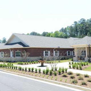 A modern brick building with a well-maintained landscape and adjacent road.