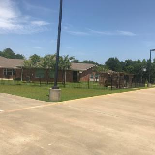 A sunny day at a community facility featuring a basketball court and green space.