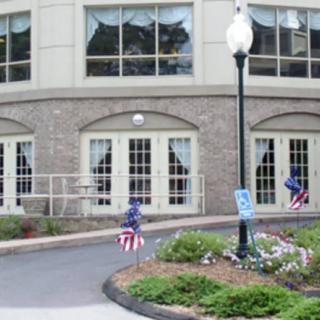 A building with large windows decorated with patriotic flags near a landscaped pathway.