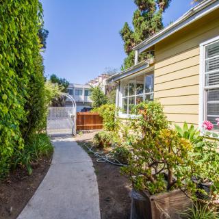A charming pathway beside a house with a garden on a sunny day.