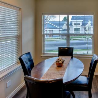 A cozy dining area with a wooden table and four chairs by the window, allowing natural light to fill the room.
