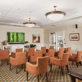 A well-arranged conference room with orange chairs, a large TV, and decorative artwork.