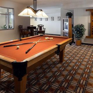 A cozy game room featuring a pool table with crossed cues, lit by elegant overhead lamps.