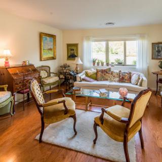 A cozy and elegant living room featuring comfortable seating, warm wooden floors, and bright natural light.