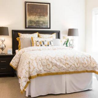 A cozy and well-decorated bedroom with a stylish bedspread, matching pillows, and elegant bedside lamps.