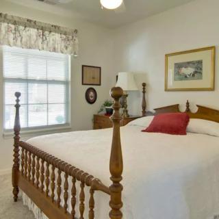 A cozy bedroom with a wooden bed, a window allowing natural light, and decorative elements.