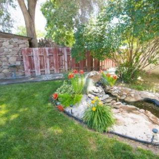 A serene garden featuring a small pond surrounded by greenery and flowers.