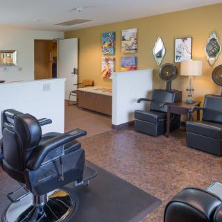 A well-furnished barbershop interior with chairs, mirrors, and a waiting area.