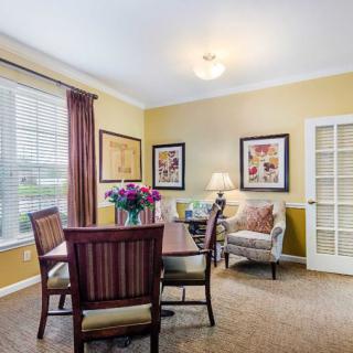 A cozy dining room with a table set for four, adorned with fresh flowers and decorated with artwork.