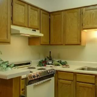 A compact kitchen with wooden cabinets, a stove, and a sink.