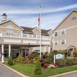 A residential building with a landscaped entrance and flagpole in the front yard.