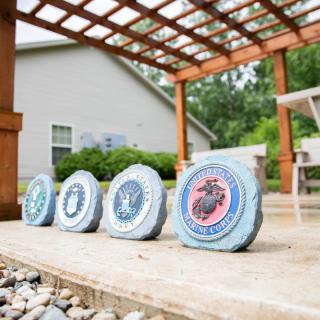 Decorative stones featuring military emblems placed on a patio under a wooden pergola.