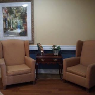 A cozy seating area featuring two upholstered chairs and a small side table with artwork on the wall.