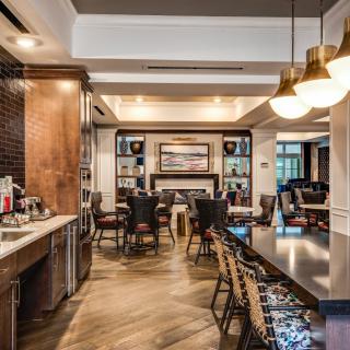 A modern and cozy restaurant interior featuring a mix of dining and bar seating with elegant lighting fixtures.