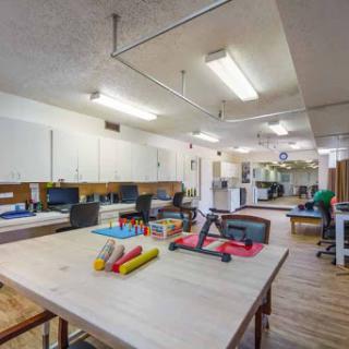A well-equipped therapy room designed for rehabilitation, featuring a spacious layout and various tools for physical activities.