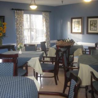 A cozy dining room with neatly arranged tables and chairs, blue walls, and decorative elements.