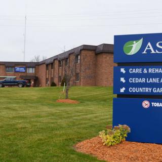 A healthcare facility with a prominent sign and well-maintained lawn.