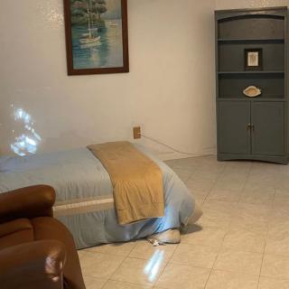 A cozy bedroom with a neatly made bed, a cabinet, and a painting on the wall.