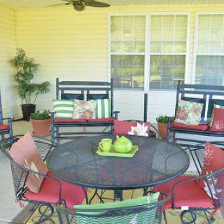 A cozy patio setup with a round metal table, colorful cushions, and decorative plants.