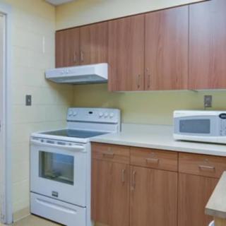 A modern kitchen with wooden cabinets, a stove, and a microwave on the countertop.