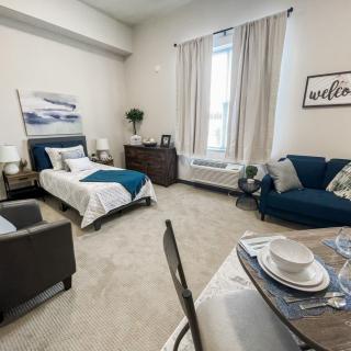 A cozy and modern apartment bedroom with a bed, sofa, and dining area.