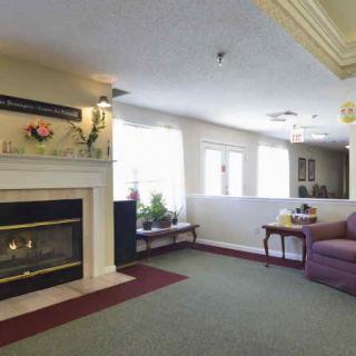 A cozy living room with a fireplace, sofa, and coffee table, featuring plants and elegant decor.