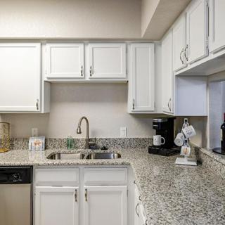 A modern kitchen with white cabinets and granite countertops.