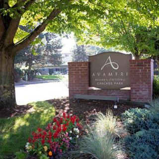 A landscaped entrance sign for a community surrounded by trees and flowers.