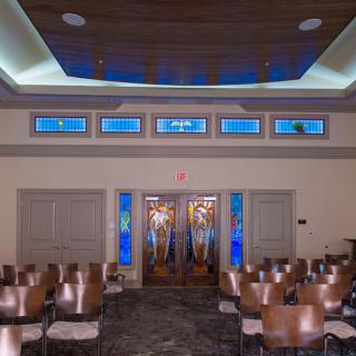 Interior of a chapel featuring stained glass and seating arrangements.