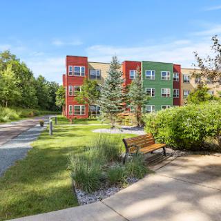 A vibrant apartment complex surrounded by lush greenery and a peaceful walkway.