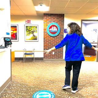 A woman in a blue shirt walks through a hospital's reception area, surrounded by artwork.