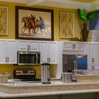 A modern kitchen with stainless steel appliances, artwork above the cabinets, and sleek decor.
