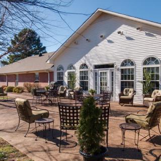 A sunny patio area with chairs and tables outside a building.