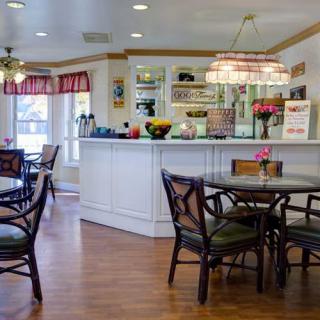 A cozy cafe interior with tables and chairs, featuring a wooden floor and a decorative counter.