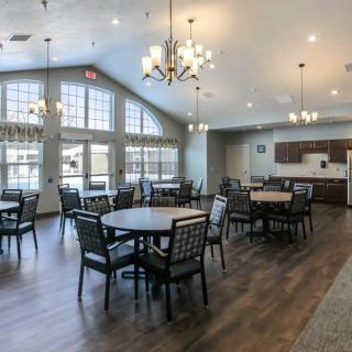 A spacious dining room interior with tables, chairs, and chandeliers.