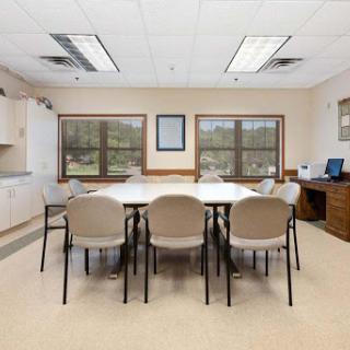 A spacious meeting room equipped with a long table, chairs, and a computer workstation.