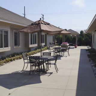 A sunny outdoor patio area with tables, chairs, and umbrellas.