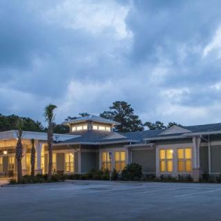 An exterior view of a building with lights on under a cloudy evening sky.
