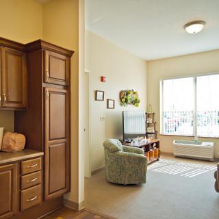A cozy living room with a view, featuring a television and comfortable seating adjacent to a kitchen area.