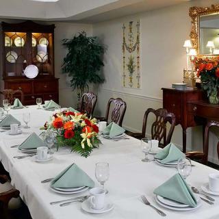 An elegantly set dining room table with floral centerpiece and classic furniture.