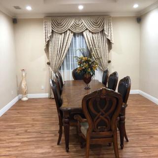 A classic dining room setup with a wooden table and chairs, elegant curtains, and a floral centerpiece.