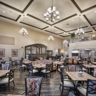 A spacious and elegantly designed restaurant dining area with chandeliers and wooden flooring.