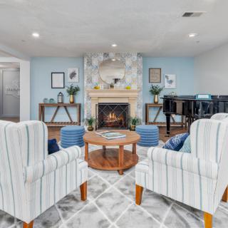 A cozy living room featuring a fireplace, armchairs, and a coffee table in a well-decorated setting.