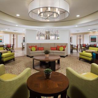 A modern lobby area with comfortable seating and a central chandelier.