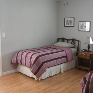 A cozy bedroom with a single bed, striped bedding, and wooden furnishings.