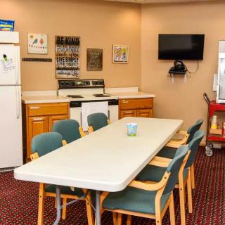 A kitchen and dining area with a table, chairs, television, and appliances.