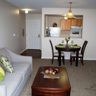 A cozy apartment interior featuring a living room, dining area, and kitchen.